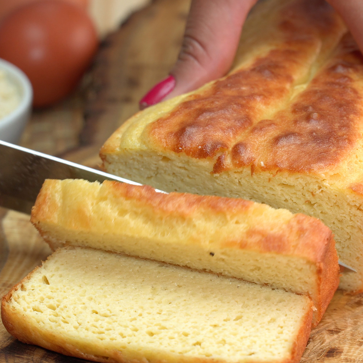 Fatias de pão de amêndoas low carb servidas ainda mornas sobre tábua de madeira.