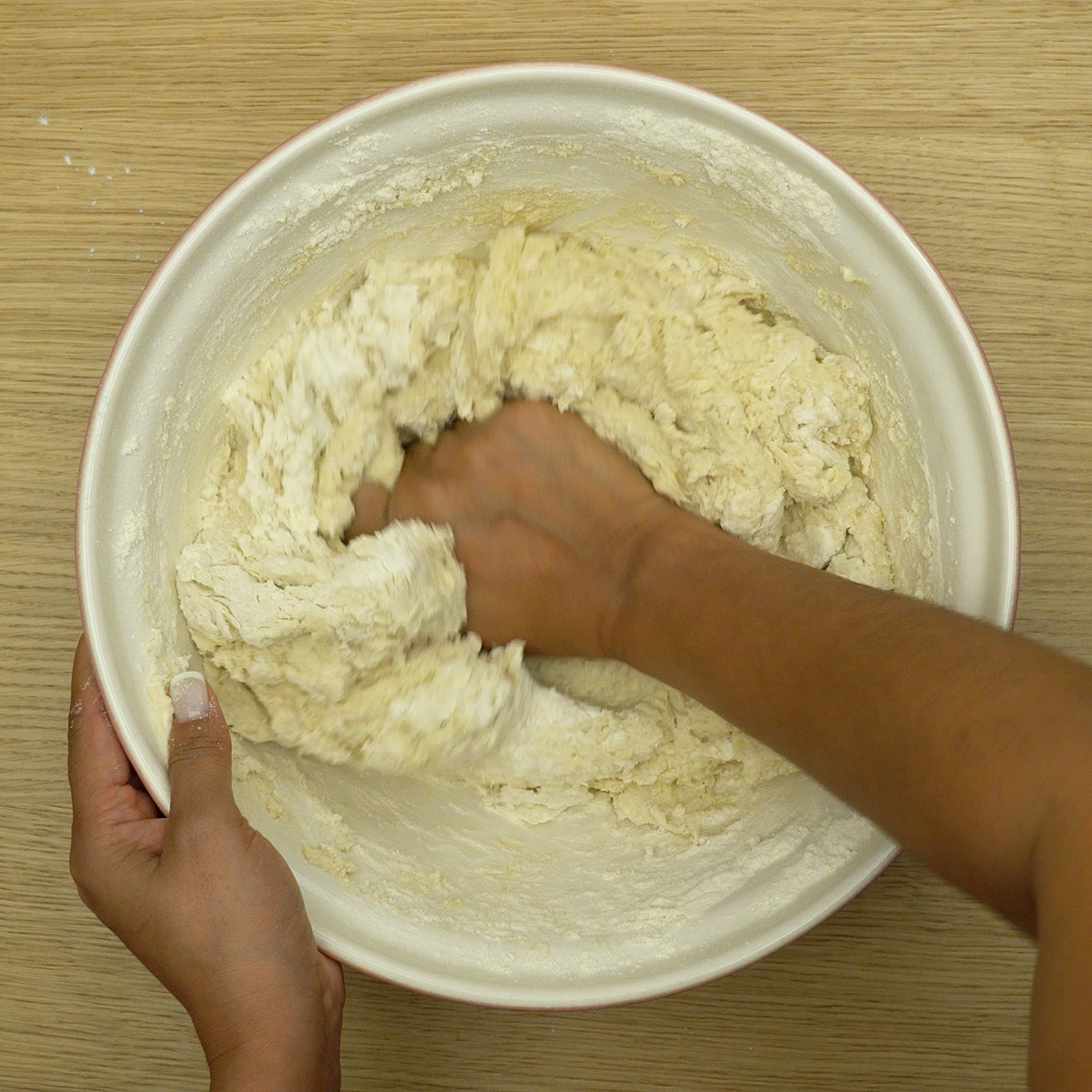 Massa de pão de cebola sendo sovada até ficar lisa e uniforme.