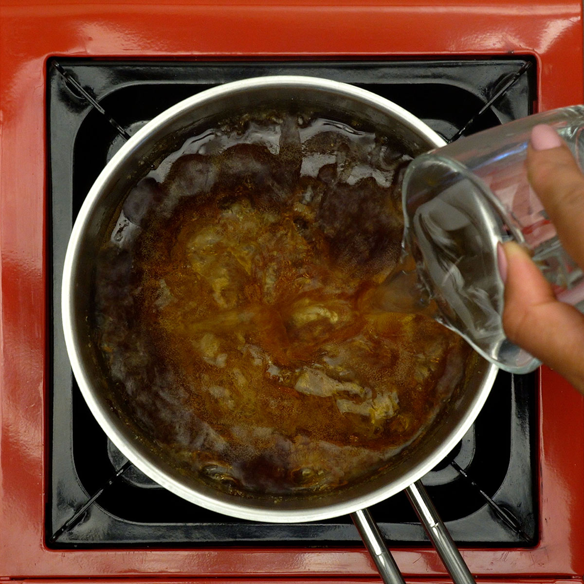 Água quente sendo adicionada ao caramelo para formar calda líquida.