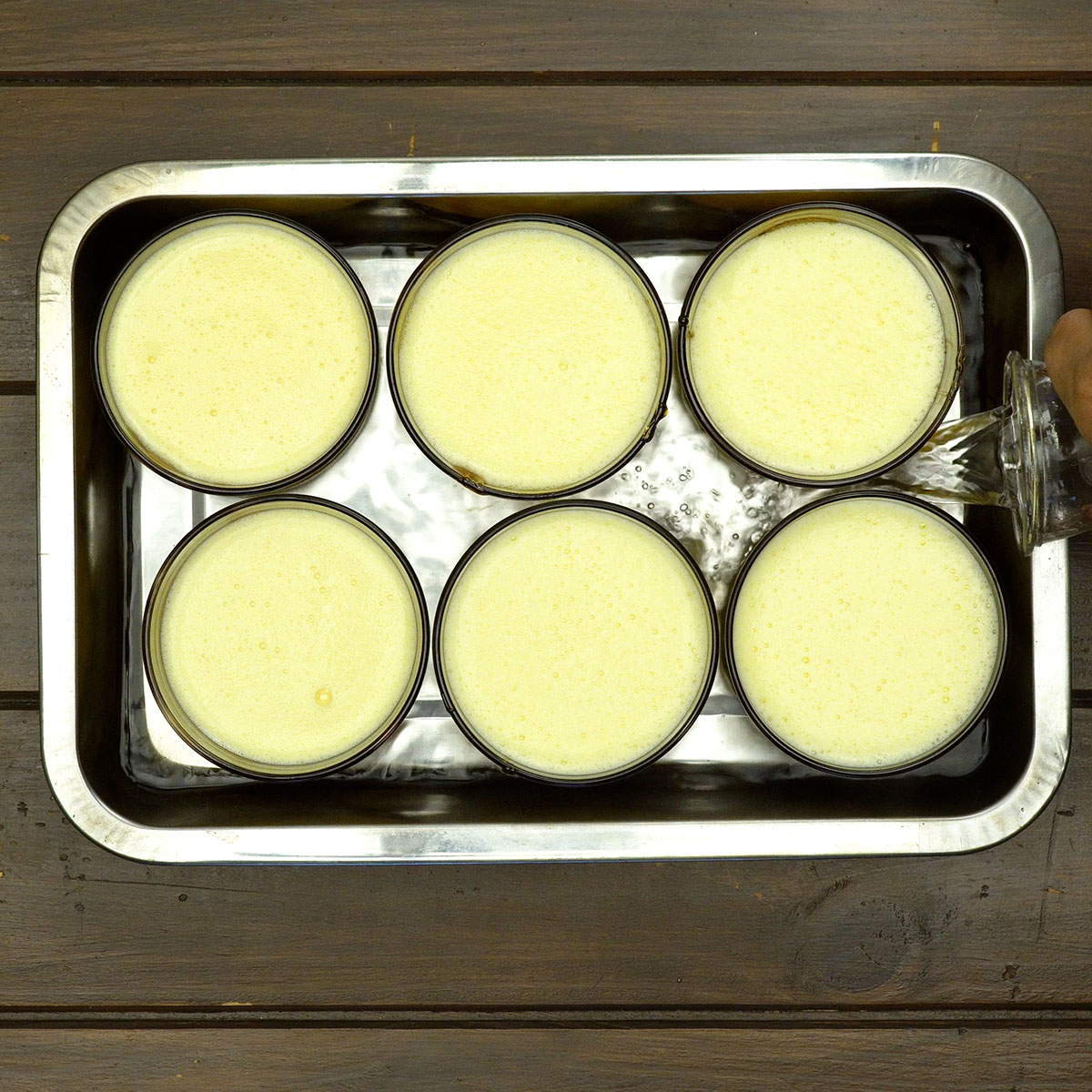 Assadeira com água quente sendo preparada para banho-maria no forno.
