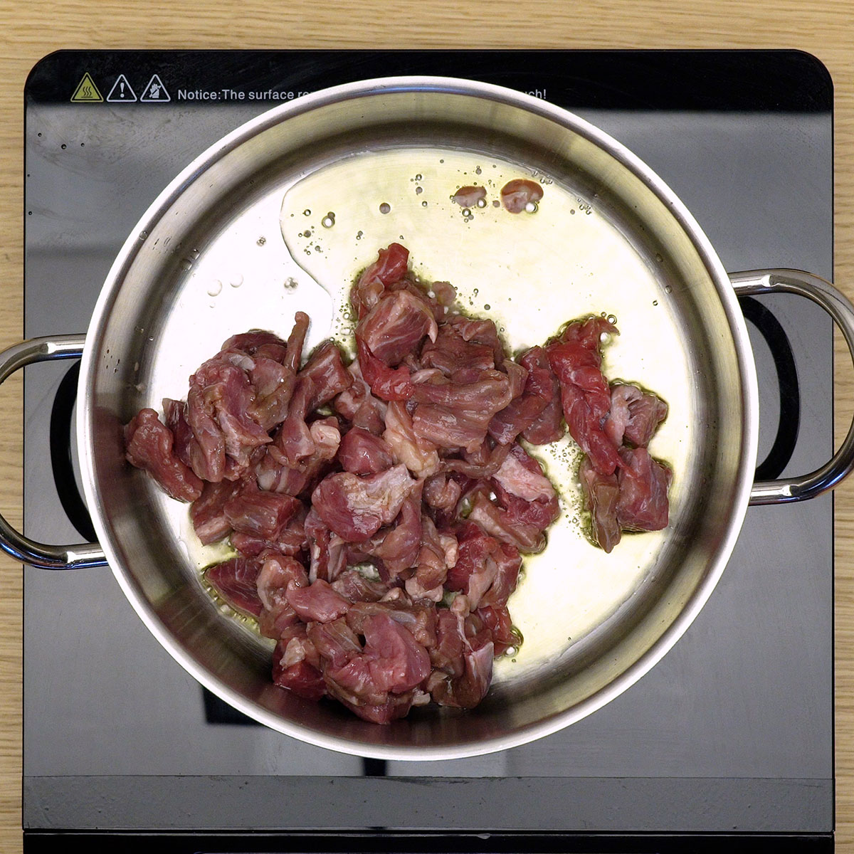 Carne bovina dourando no azeite para preparo de quibebe de mandioca com carne.