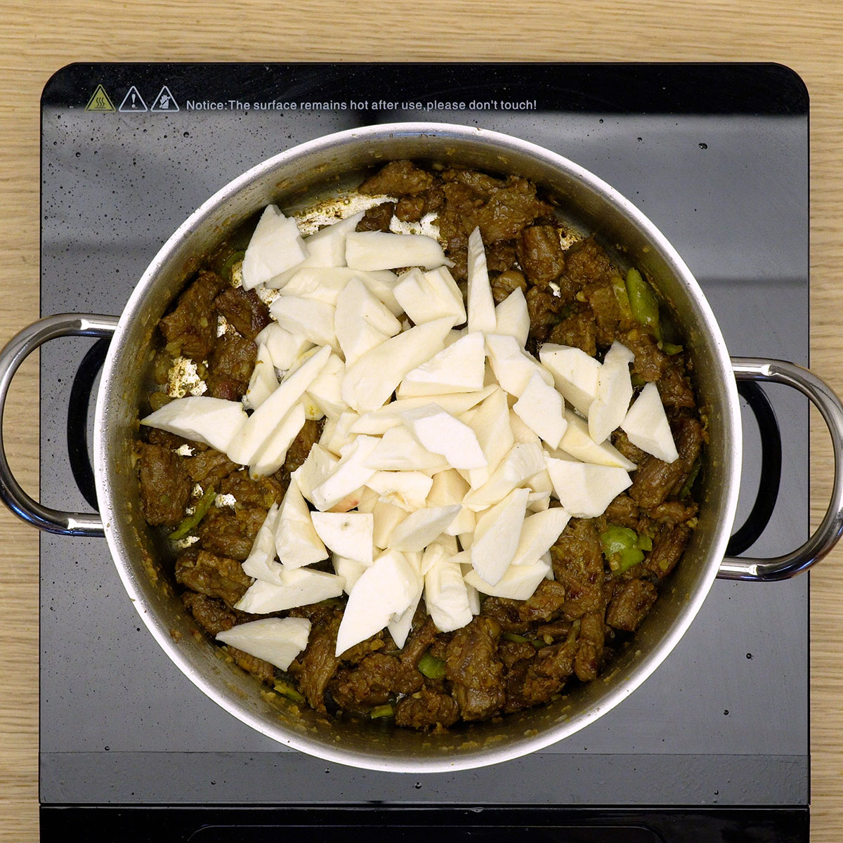 Mandioca misturada com carne e temperos na panela.