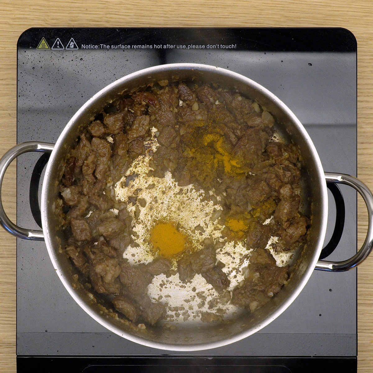 Cebola, alho e açafrão refogando junto com carne bovina.