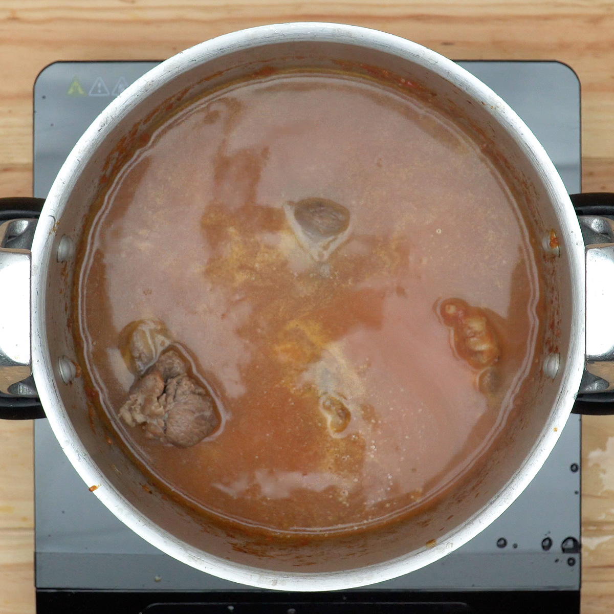 Rabada cozinhando lentamente em molho temperado e aromático