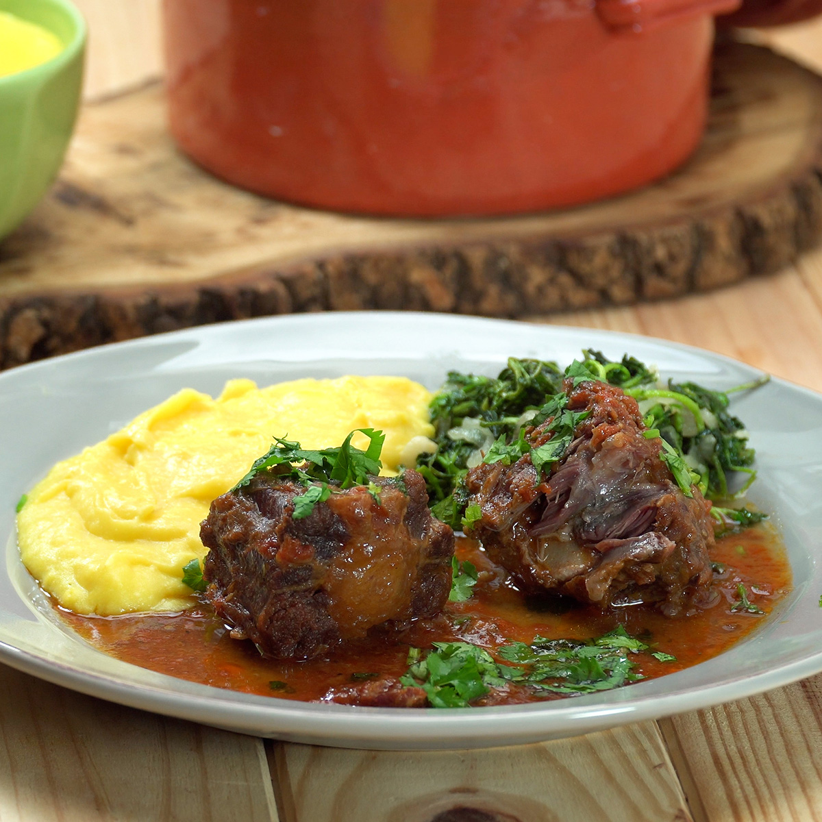 Rabada com polenta cremosa e agrião servida no prato.
