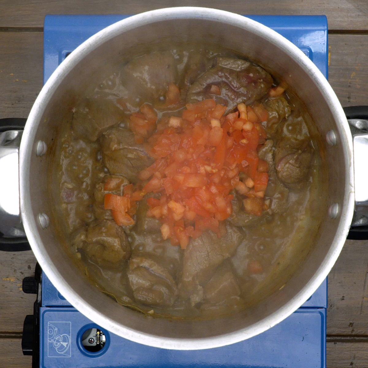 Molho de tomate cozinhando com músculo bovino na panela.