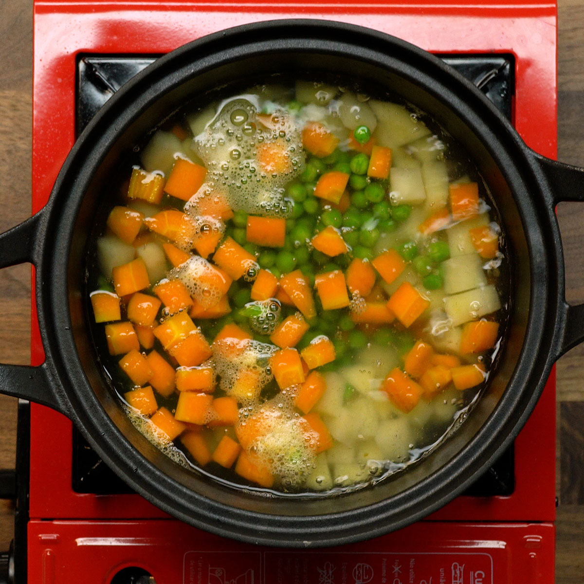 Batatas e ervilhas cozinhando para salada de maionese com ovos.