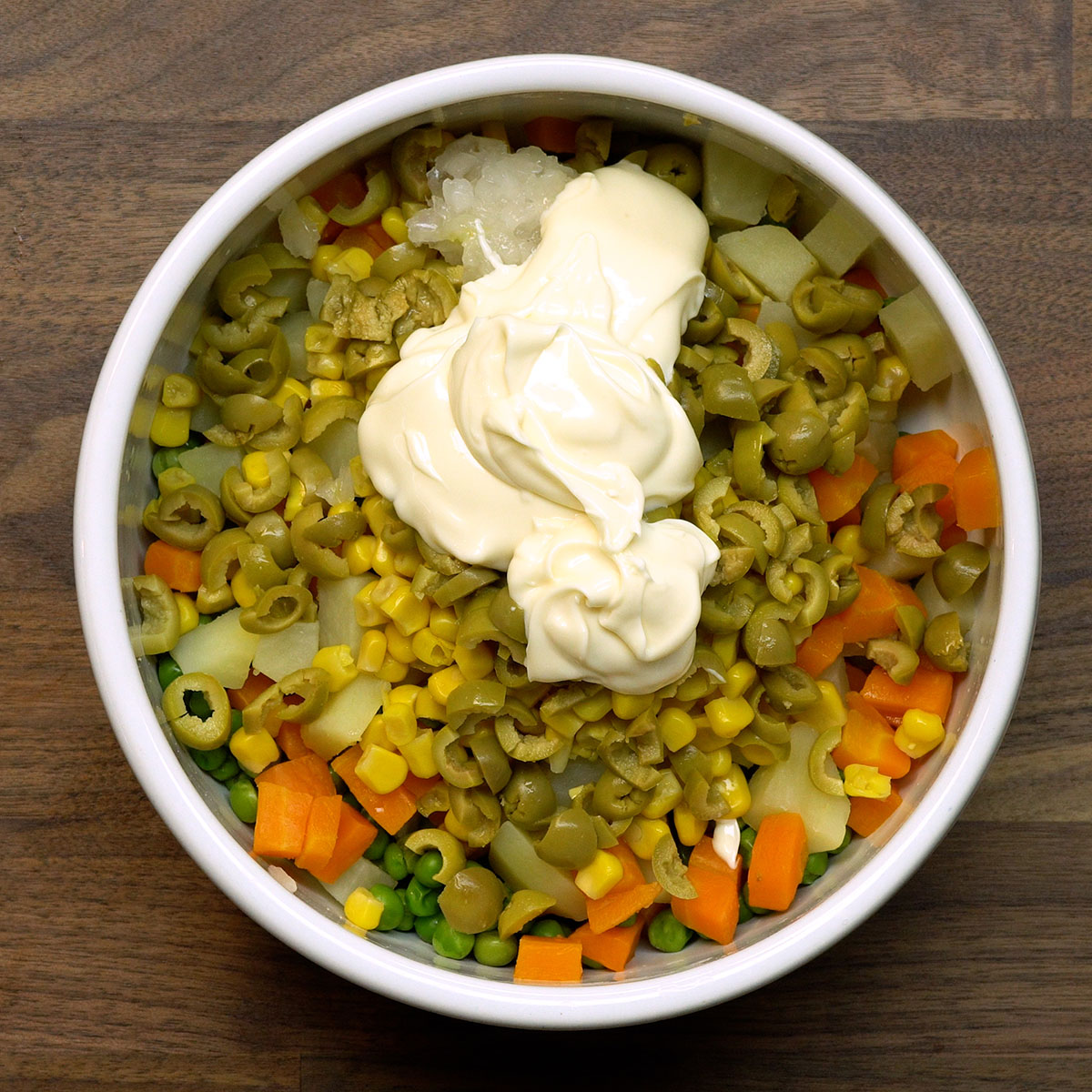 Mistura de legumes com maionese em tigela grande para salada cremosa.