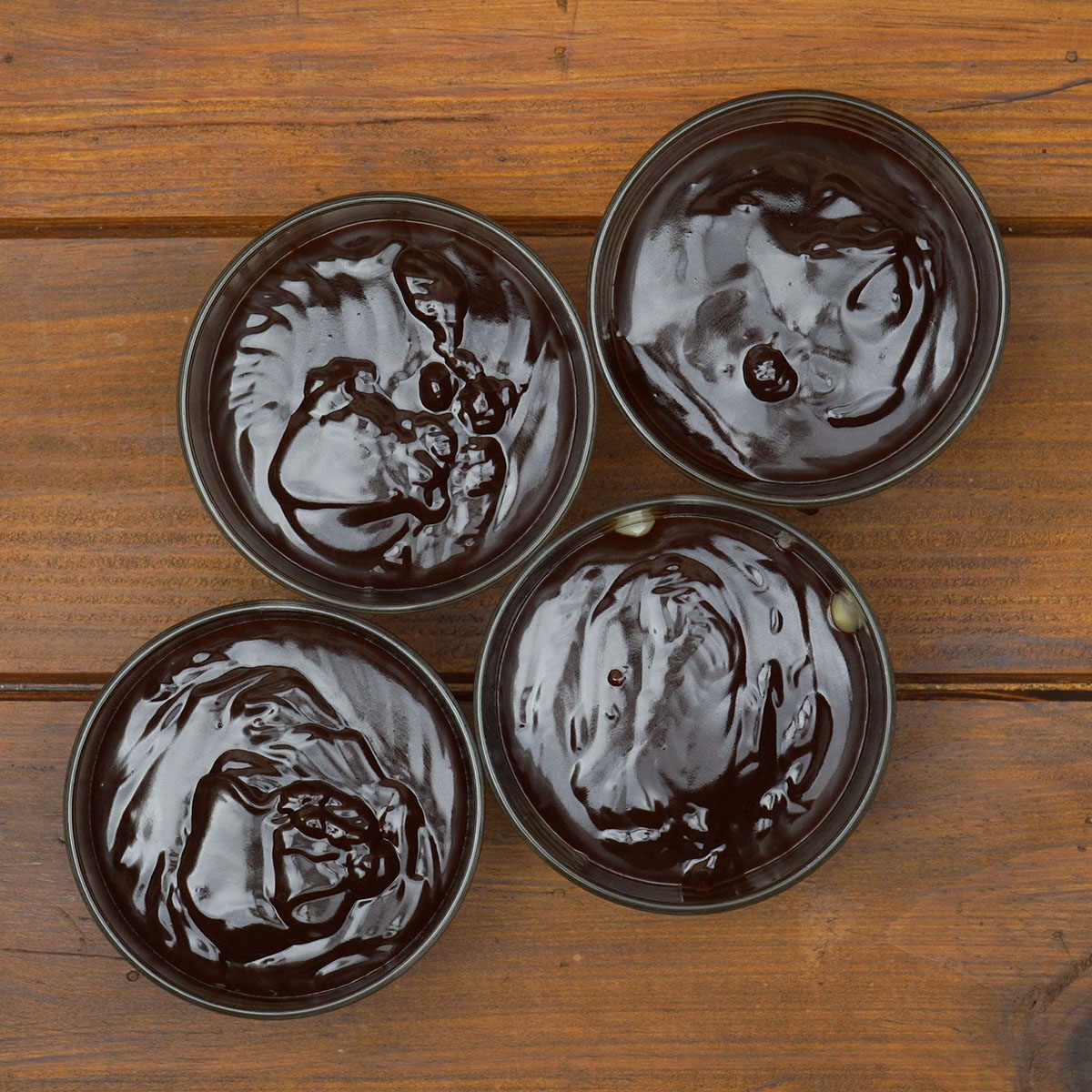 Ganache de chocolate sendo adicionada sobre o creme de coco nas taças.