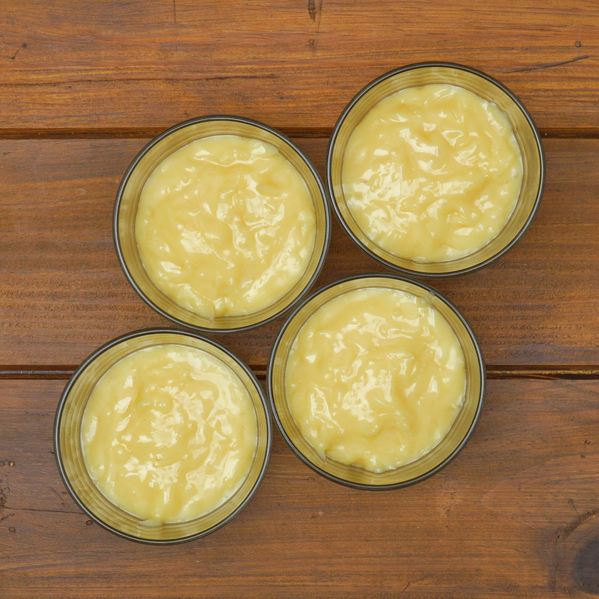 Creme de coco sendo colocado em taças individuais para sobremesa.