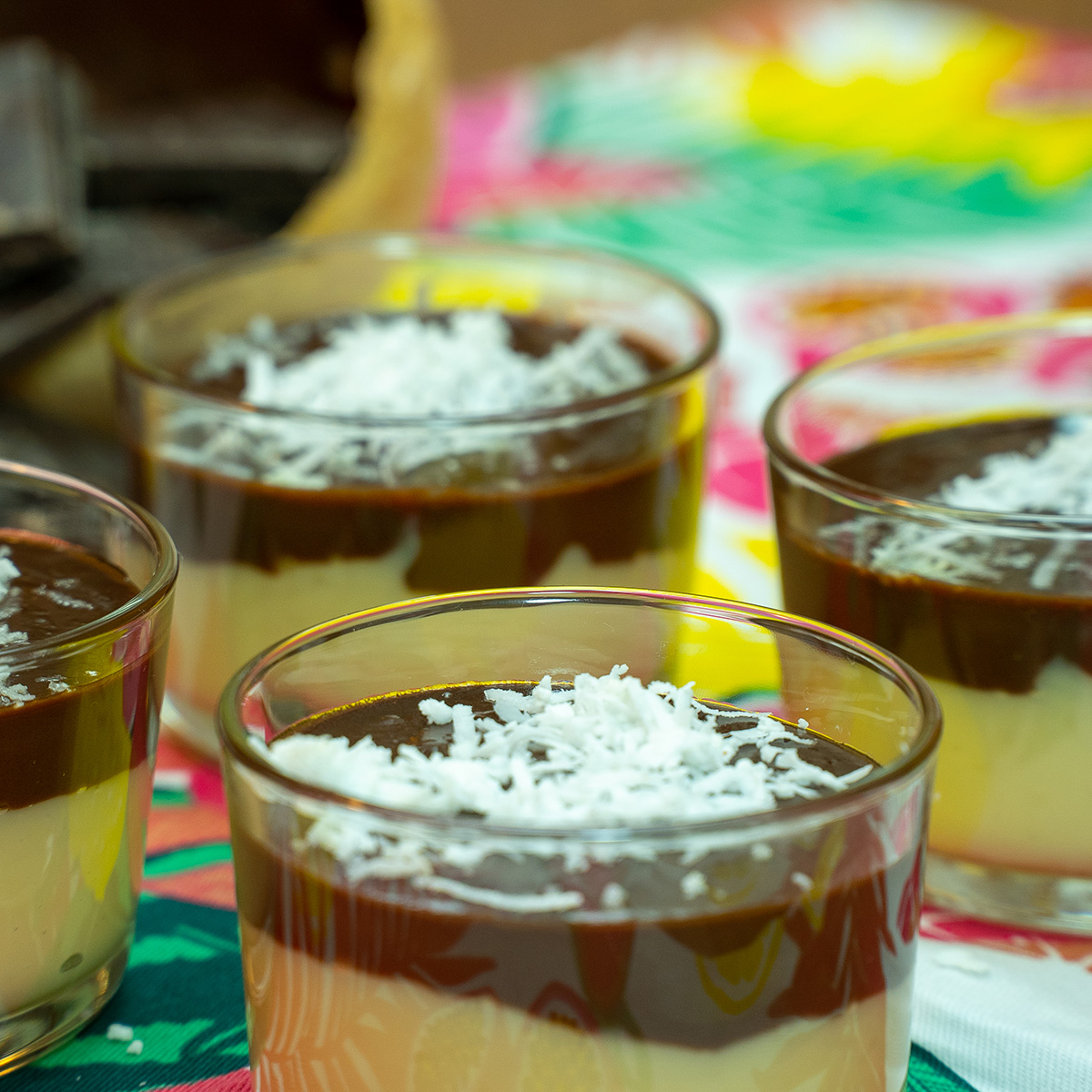 Sobremesa de coco com chocolate servida em taças com coco ralado de decoração.