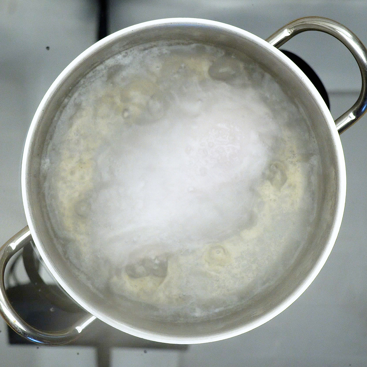 Peito de frango sendo cozido em água com sal até atingir textura macia.