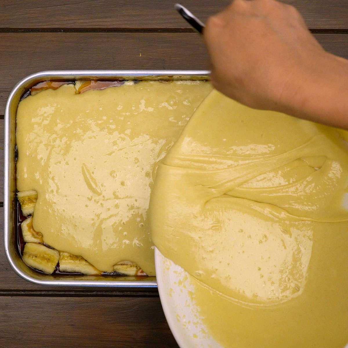 Massa espalhada sobre bananas caramelizadas na forma.
