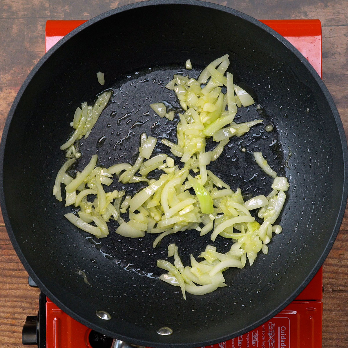 Cebola e alho sendo refogados no azeite para a torta de sardinha de liquidificador.