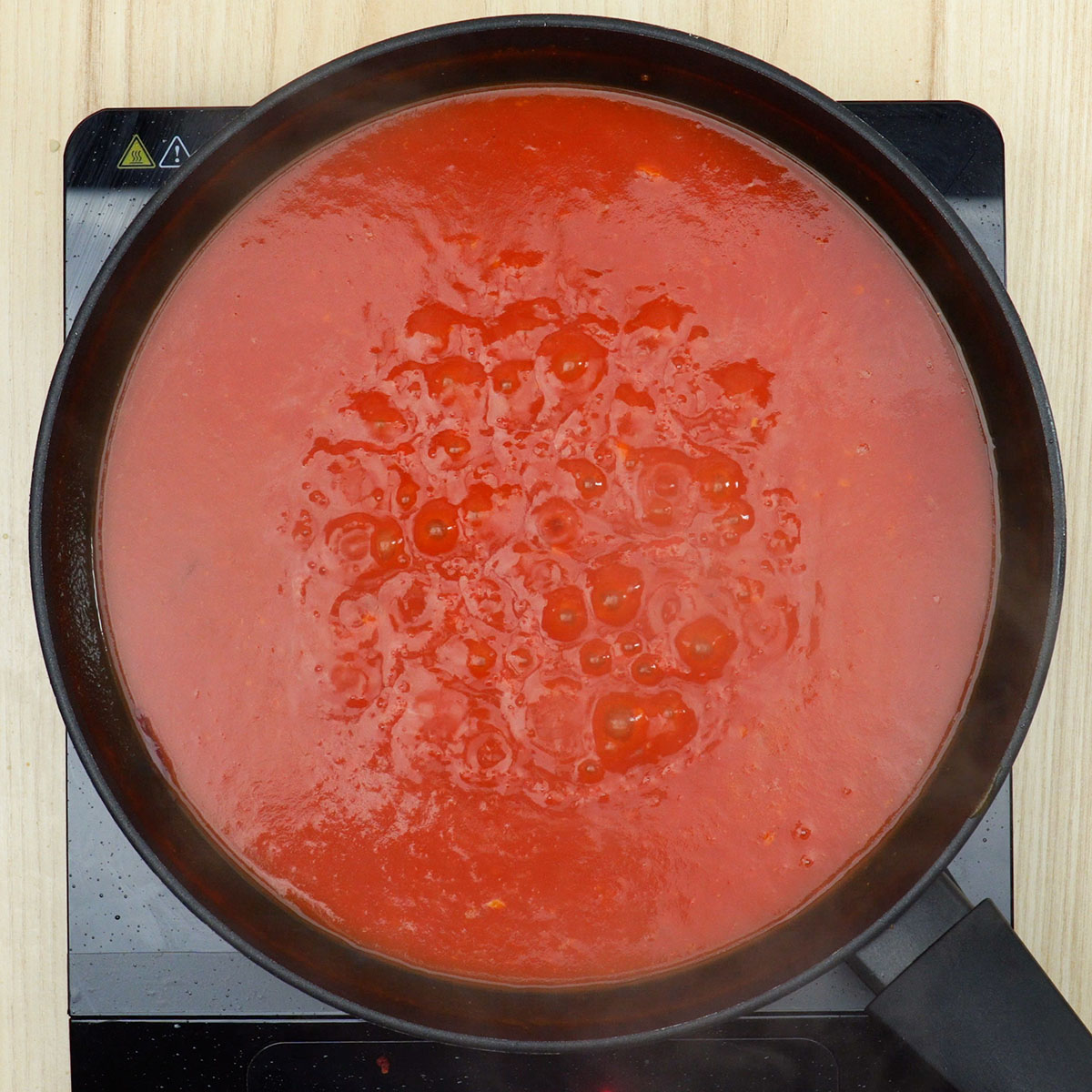 Molho de tomate sendo adicionado ao refogado de cebola e alho.