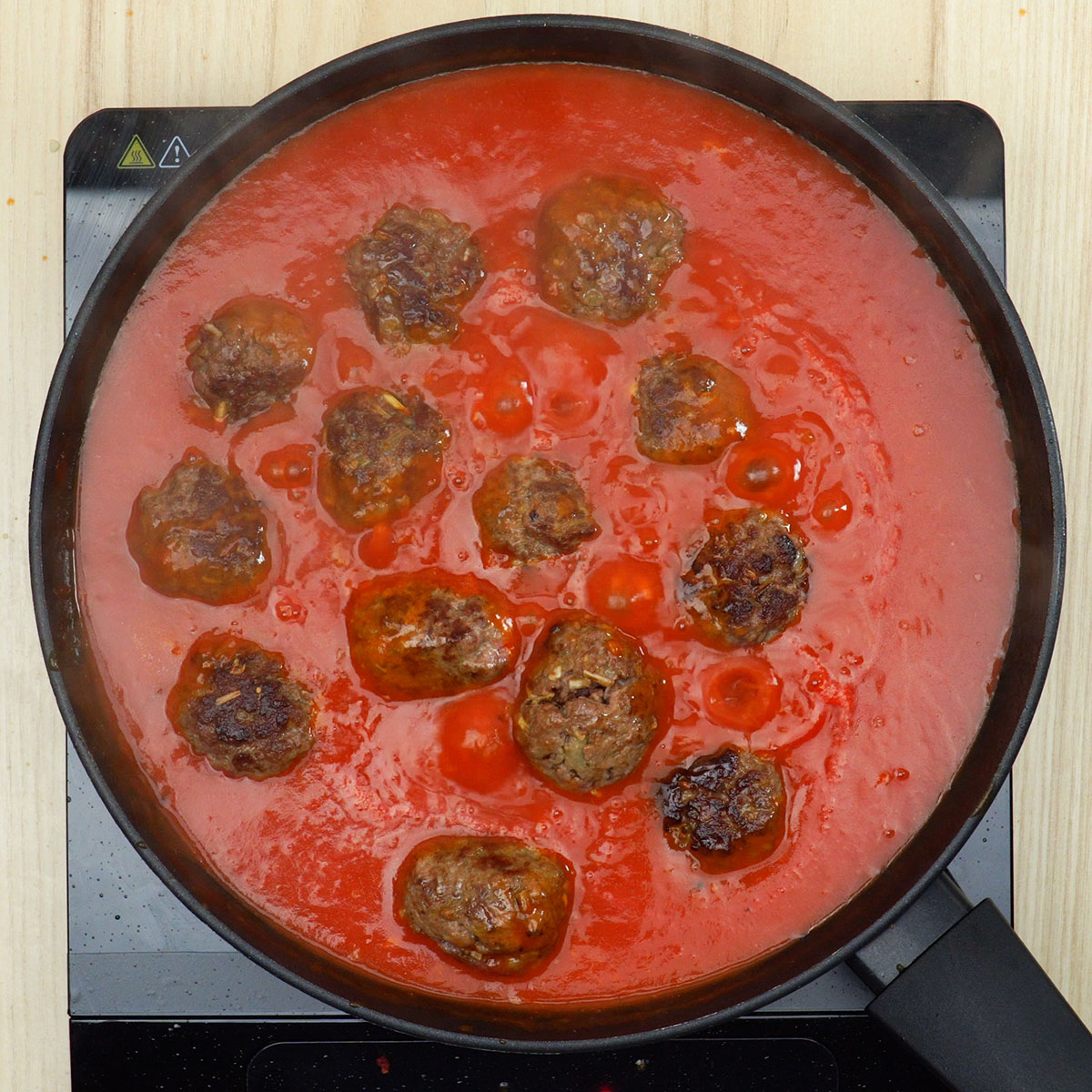 Almôndegas cozinhando no molho de tomate.