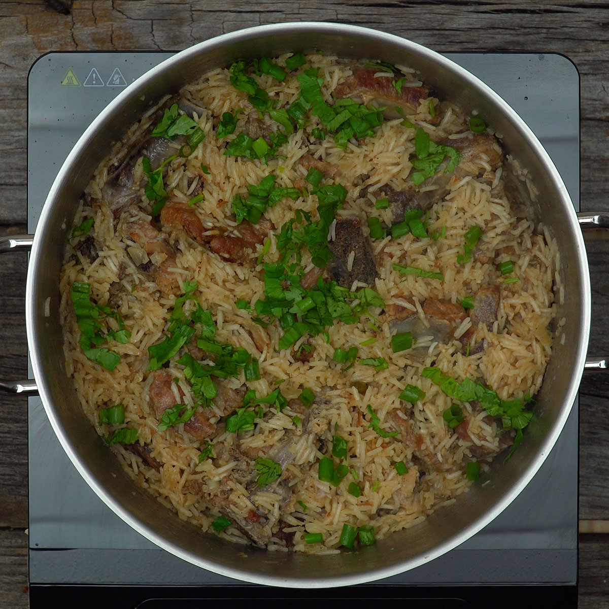 Coentros e cebolinho sendo adicionados ao arroz com suã de porco.