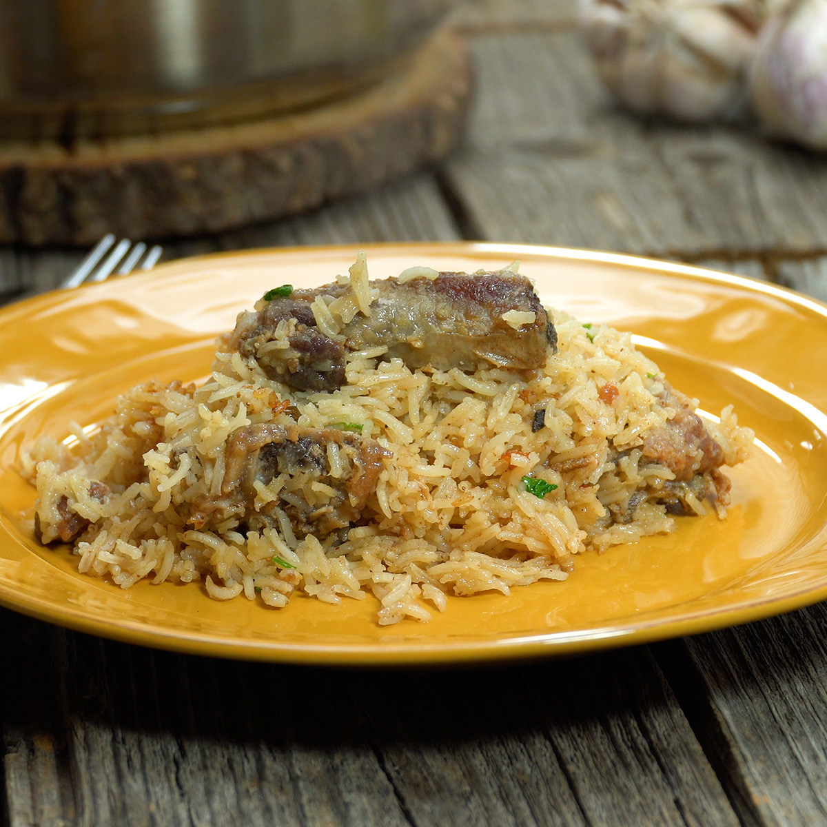 Arroz com suã de porco servido quente e finalizado com ervas frescas.