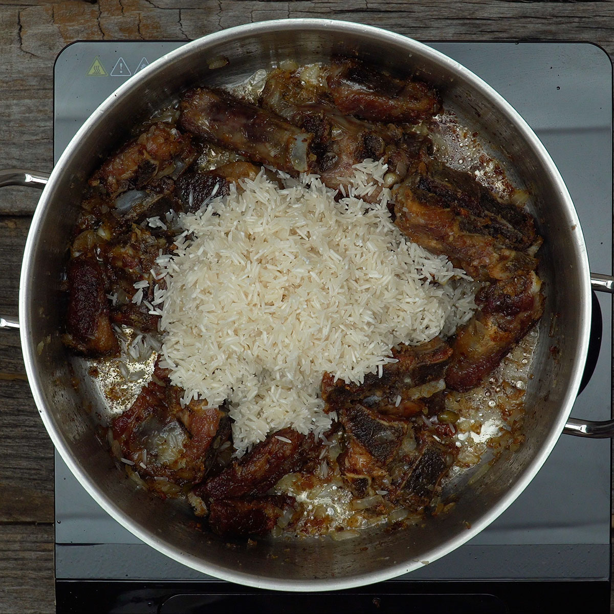 Arroz sendo misturado ao refogado de suã de porco e pimenta cumari.