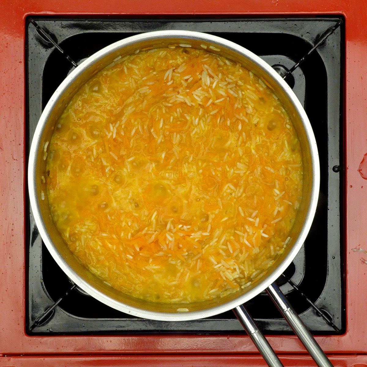 Arroz de cenoura cozinhando até ficar macio e soltinho.