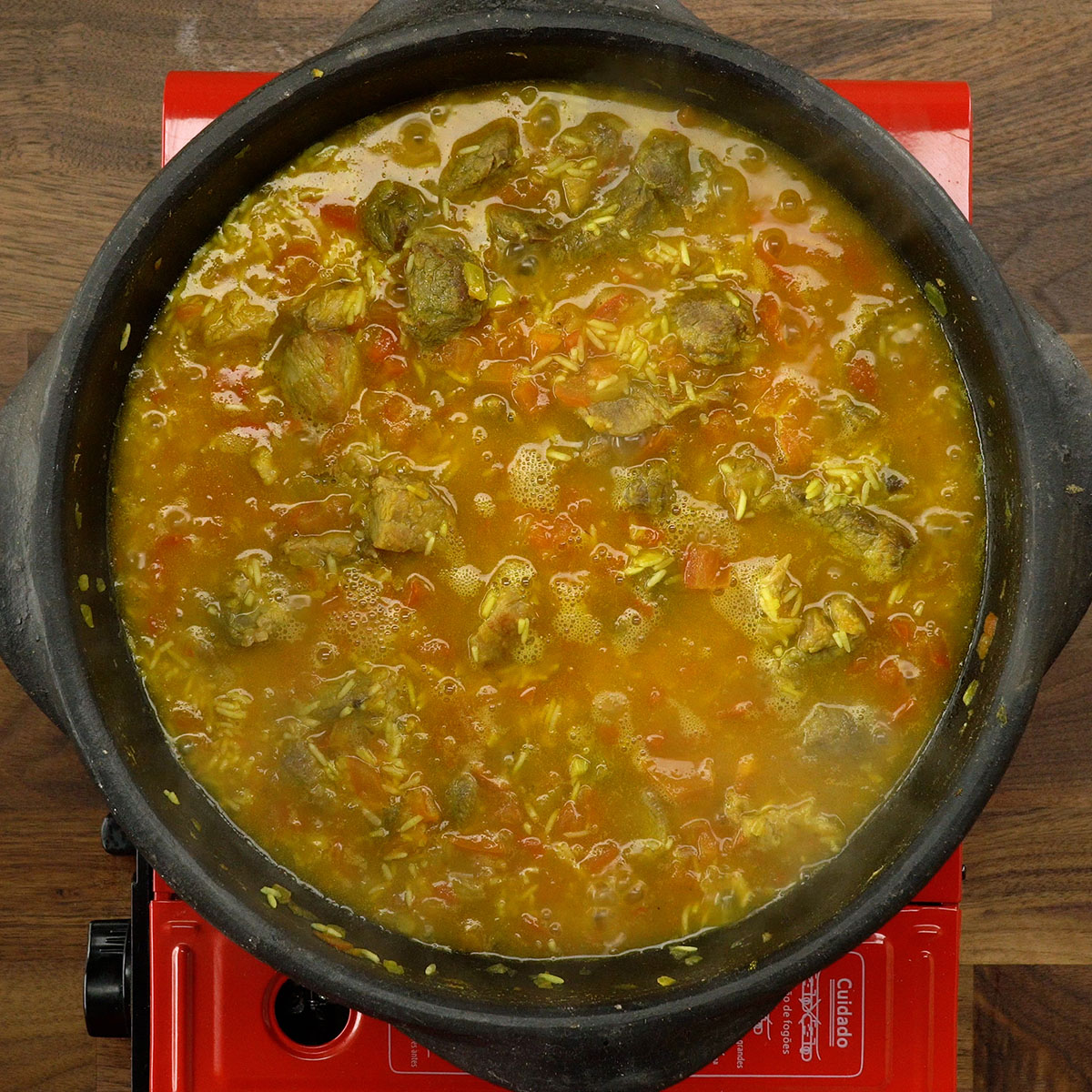 Arroz de porco cozinhando em panela tampada.