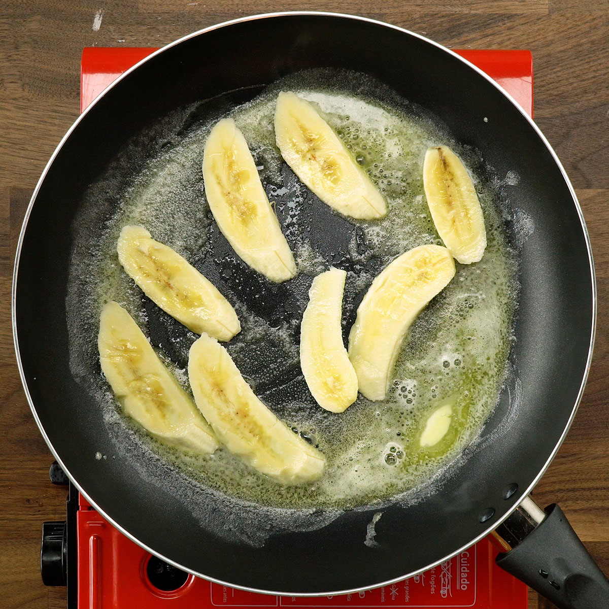Banana da prata sendo frita na frigideira com manteiga.