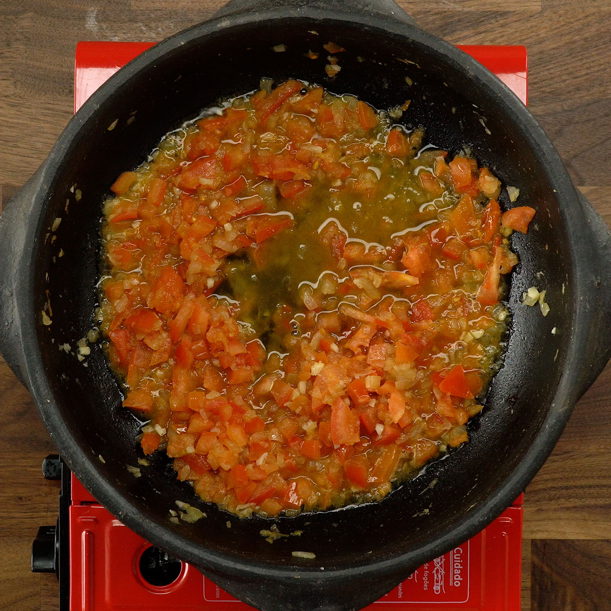 Refogado de cebola, alho e tomate sendo preparado.