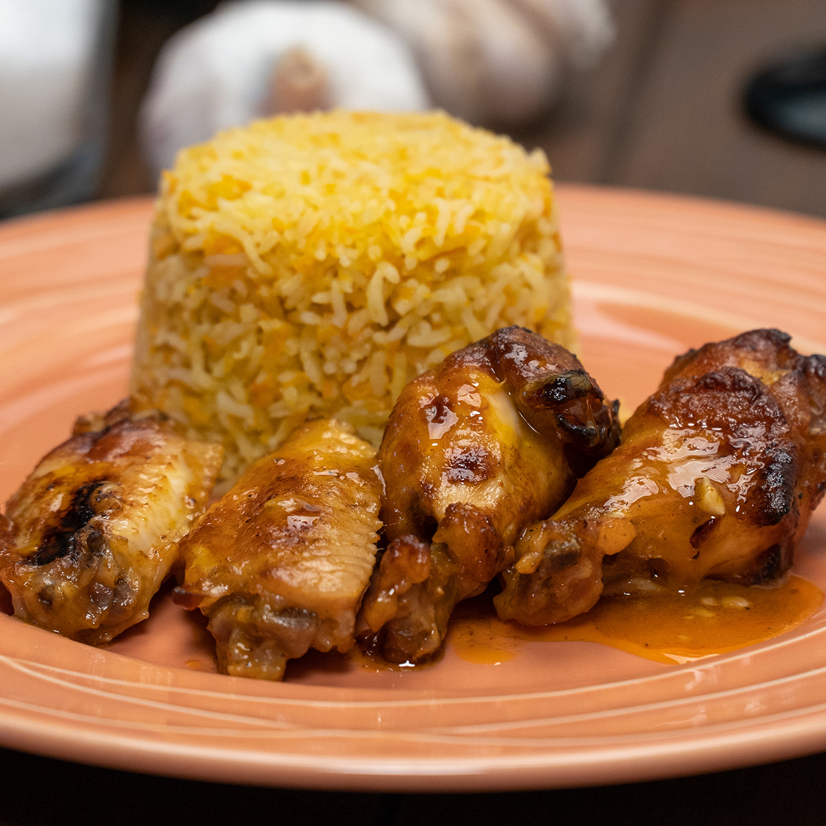 Asinhas de frango com suco de laranja servidas com arroz de cenoura.