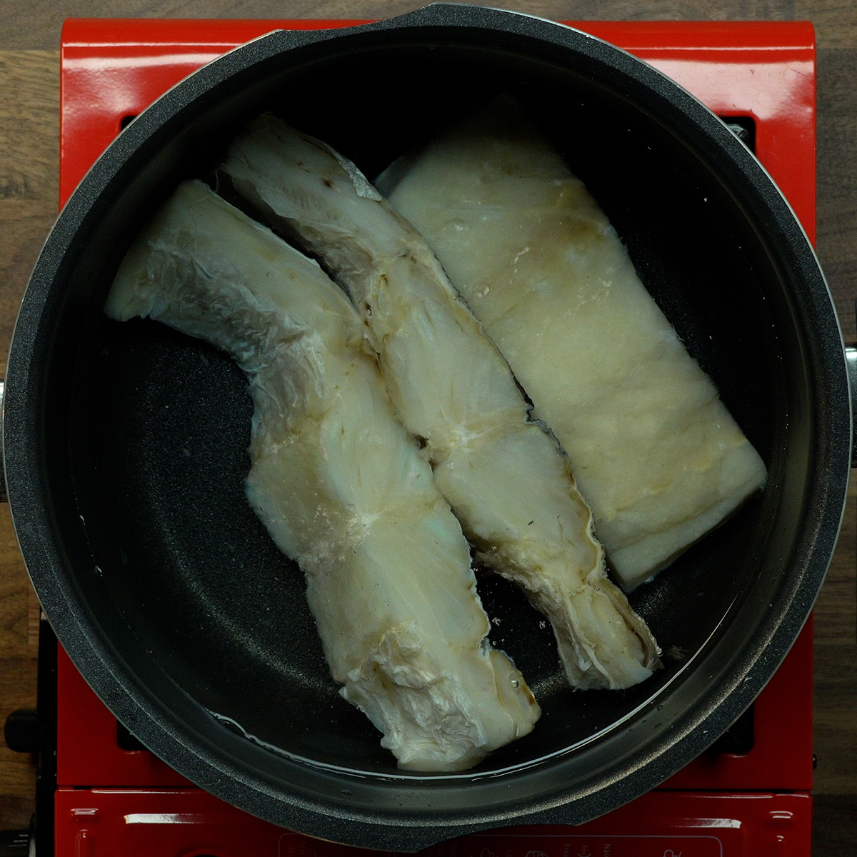 Bacalhau sendo cozido em água fervente antes de ser desfiado.