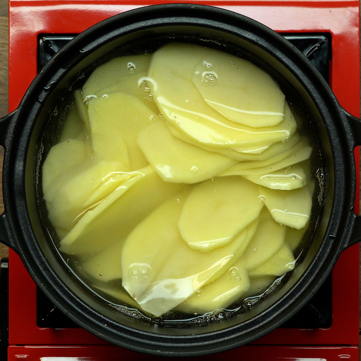 Rodelas de batata cozinhando em panela com água e sal.