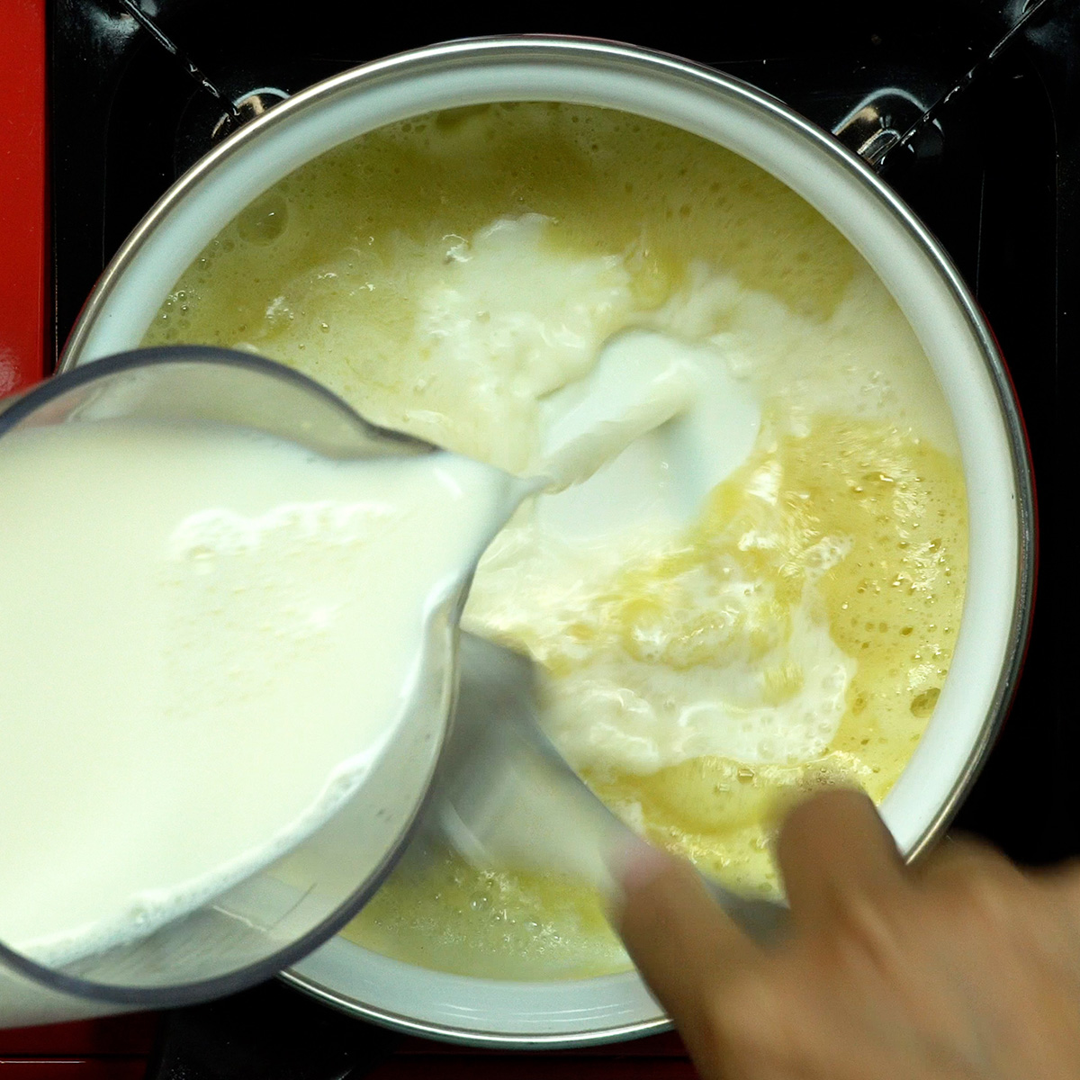 Molho branco sendo preparado em panela com leite, manteiga e farinha.