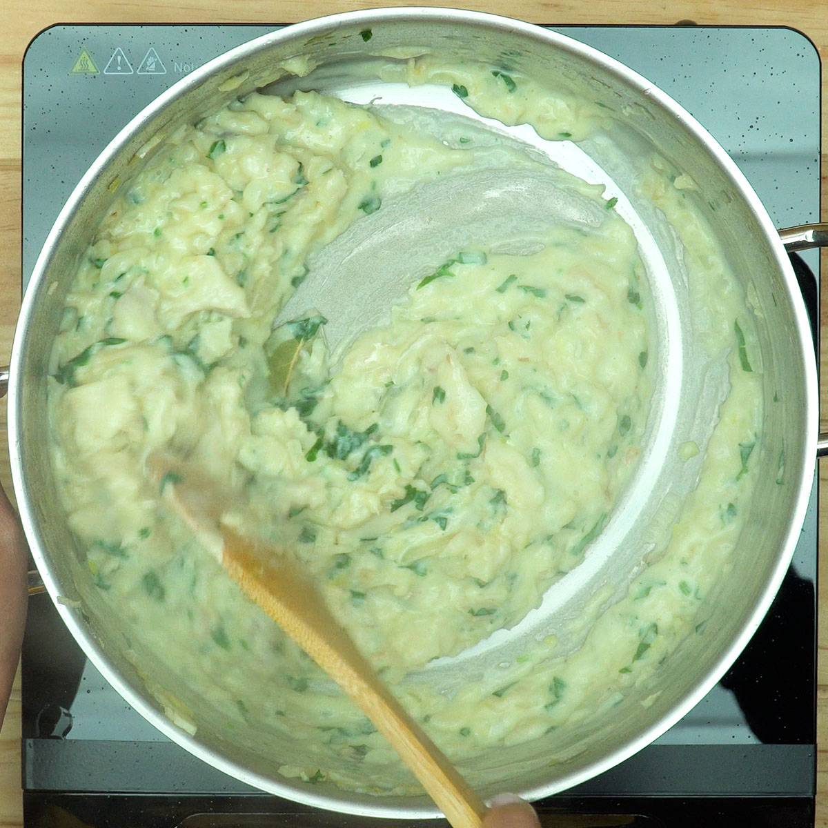 Molho cremoso de bacalhau engrossando com leite e farinha.