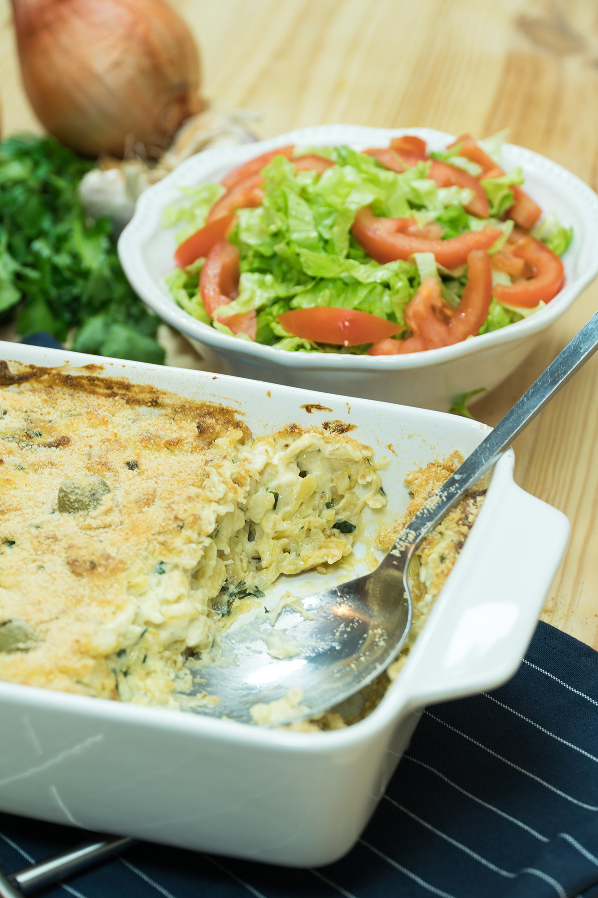 Bacalhau com natas pronto sendo servido com acompanhamentos