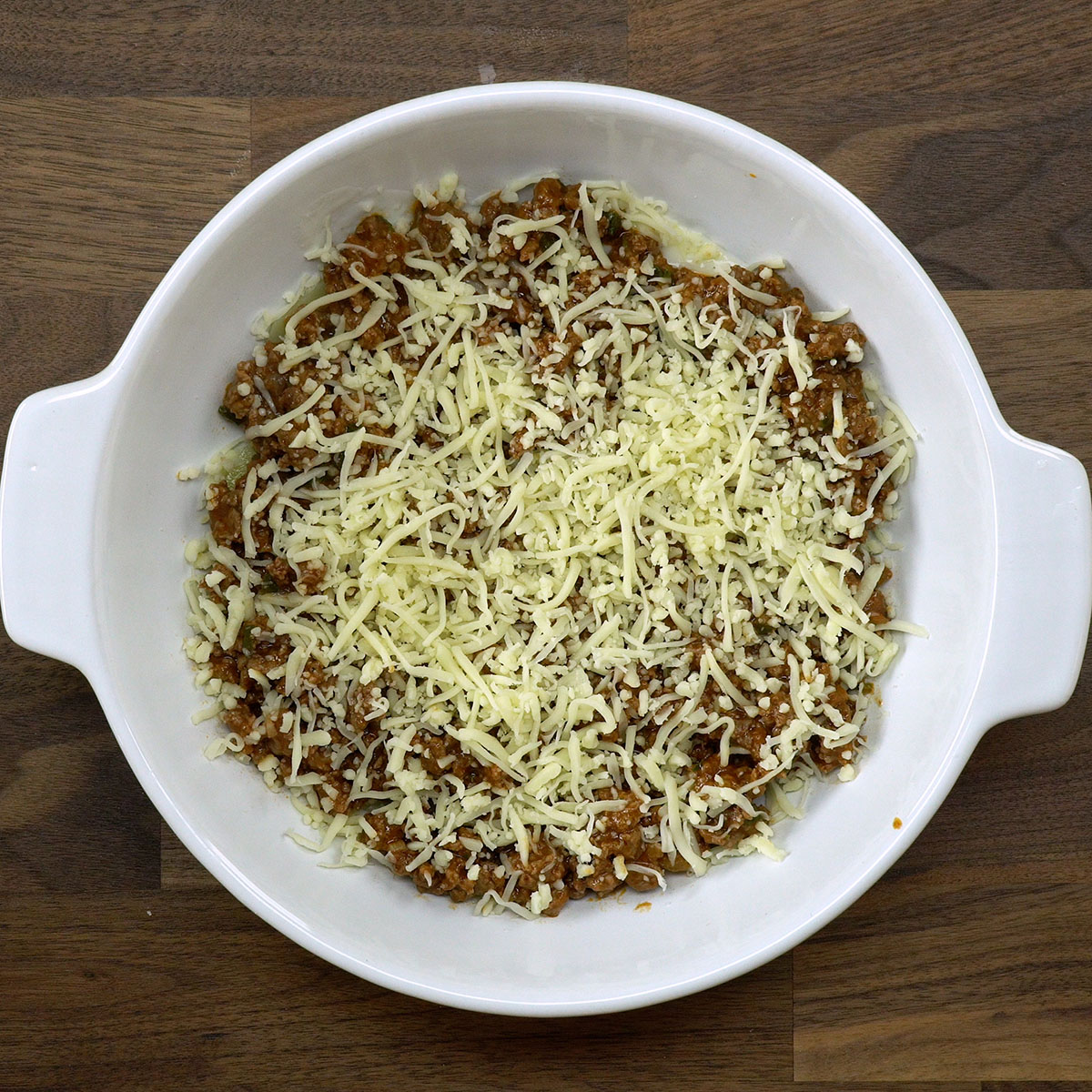 Camadas de batata, carne moída e molho branco em refratário.