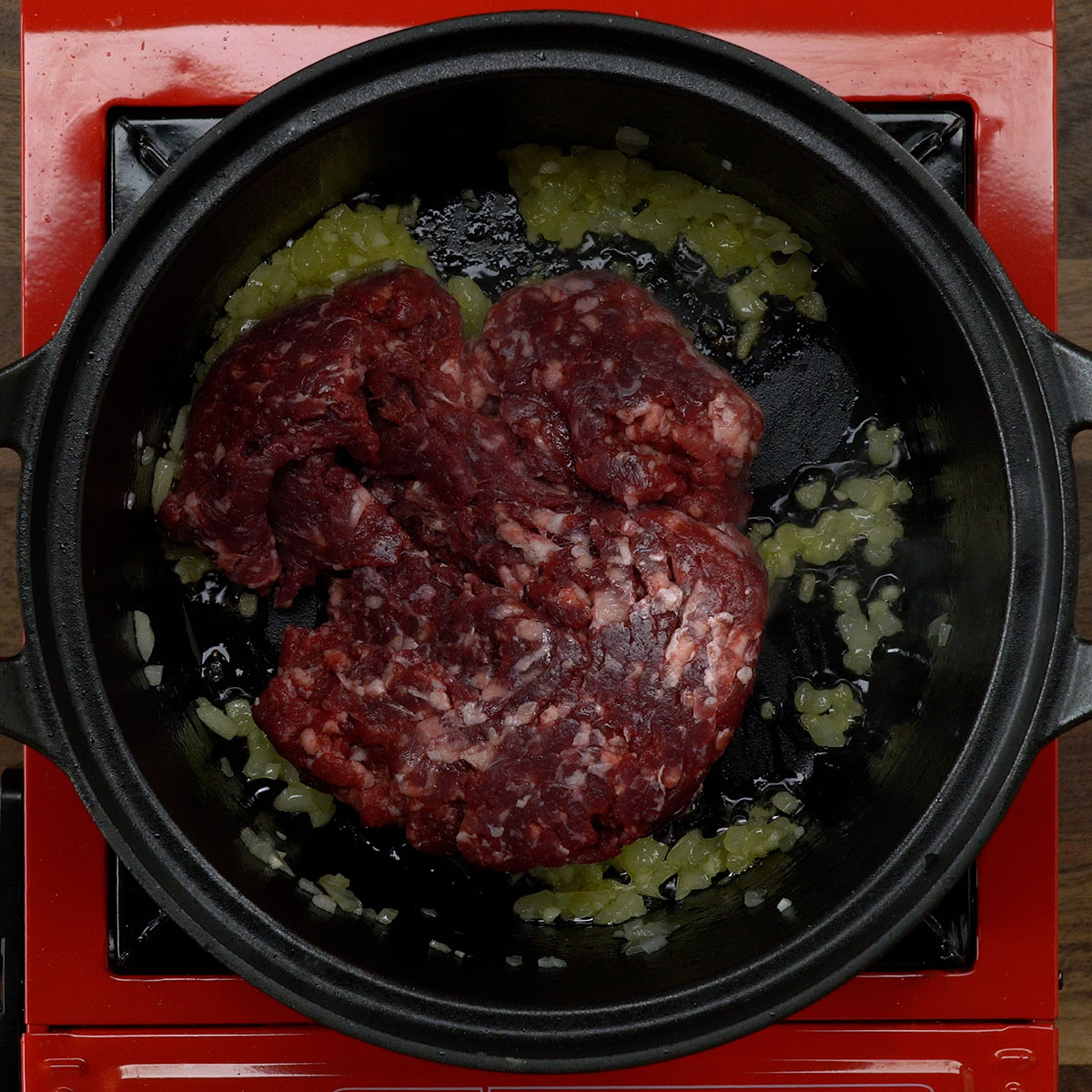 Carne moída sendo refogada com temperos em panela.