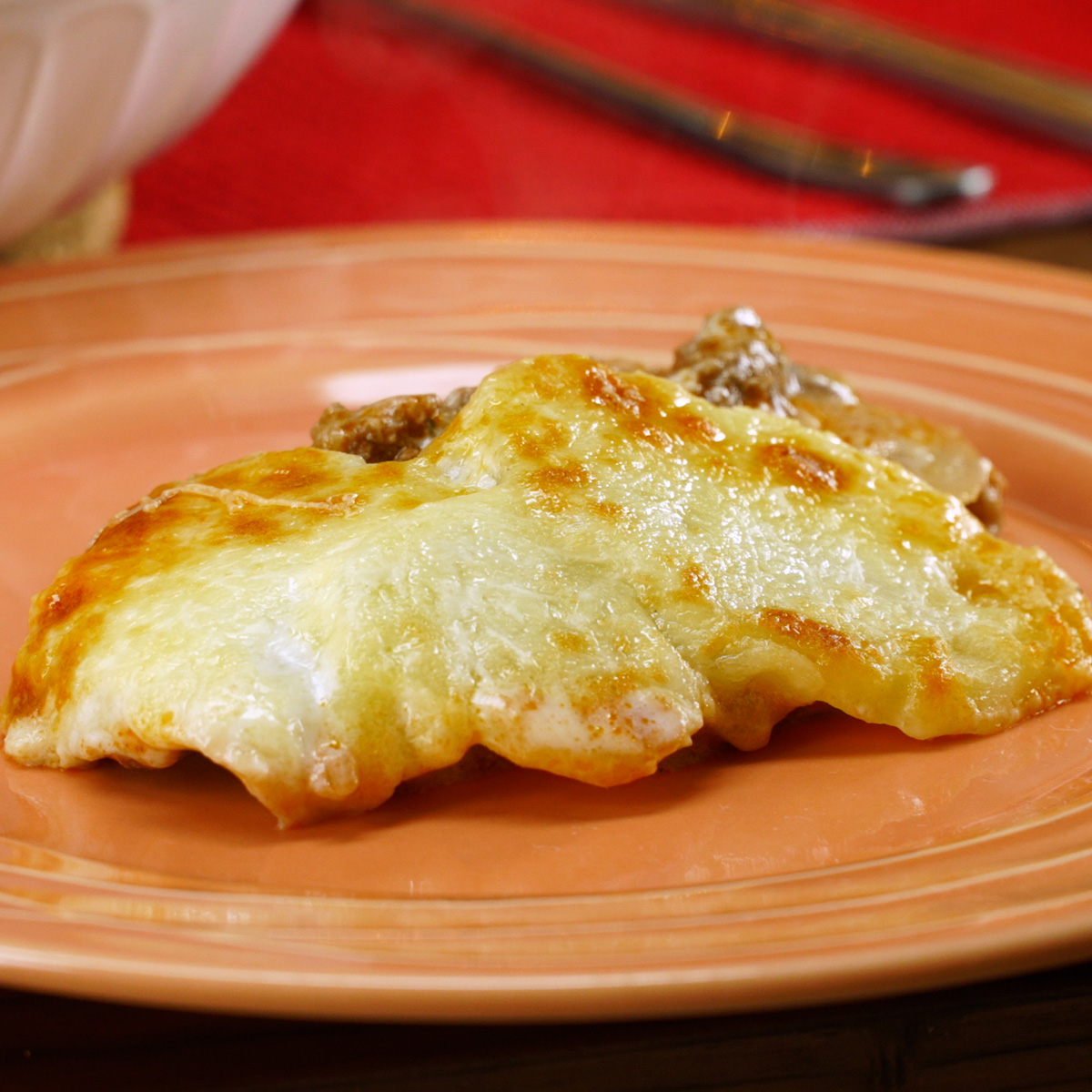 Batatas gratinadas com carne moída e molho branco servidas quentes.