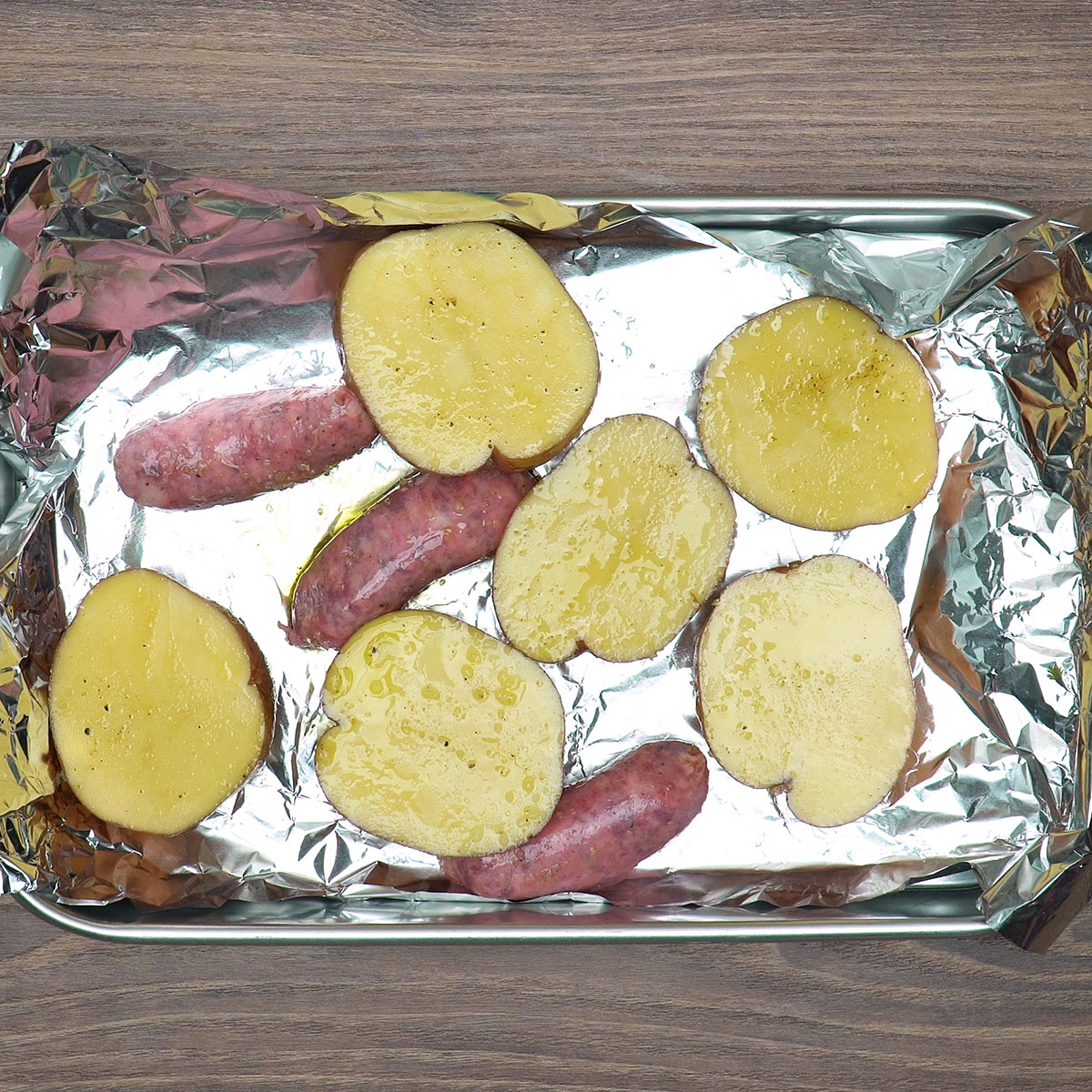 Batatas e linguiça toscana organizadas em forma para assar.
