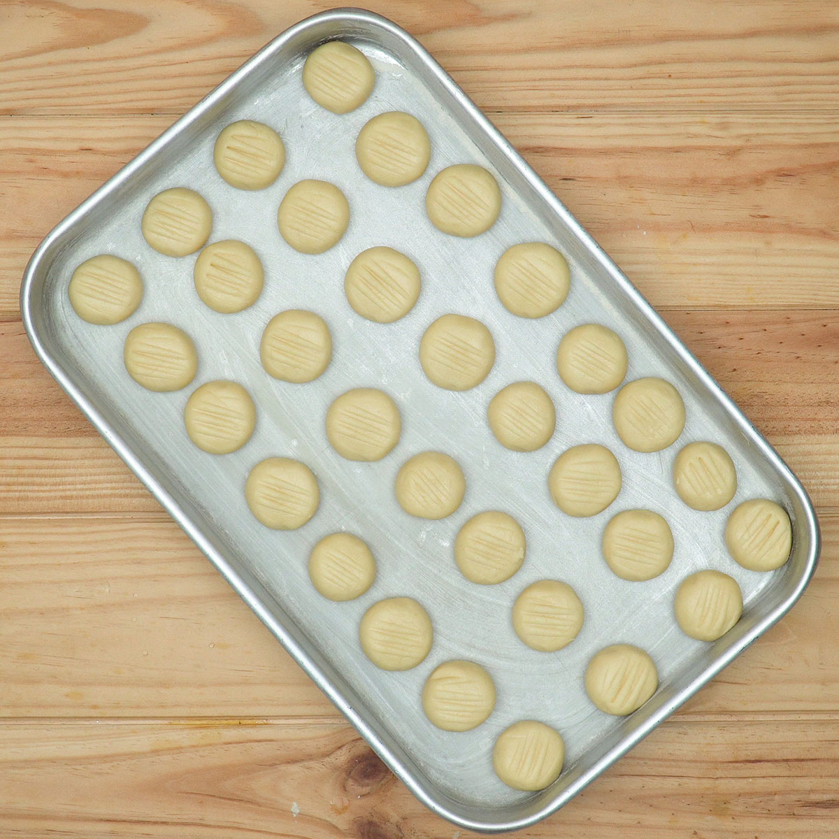 Bolinhas de massa de biscoitos de nata organizadas na assadeira.