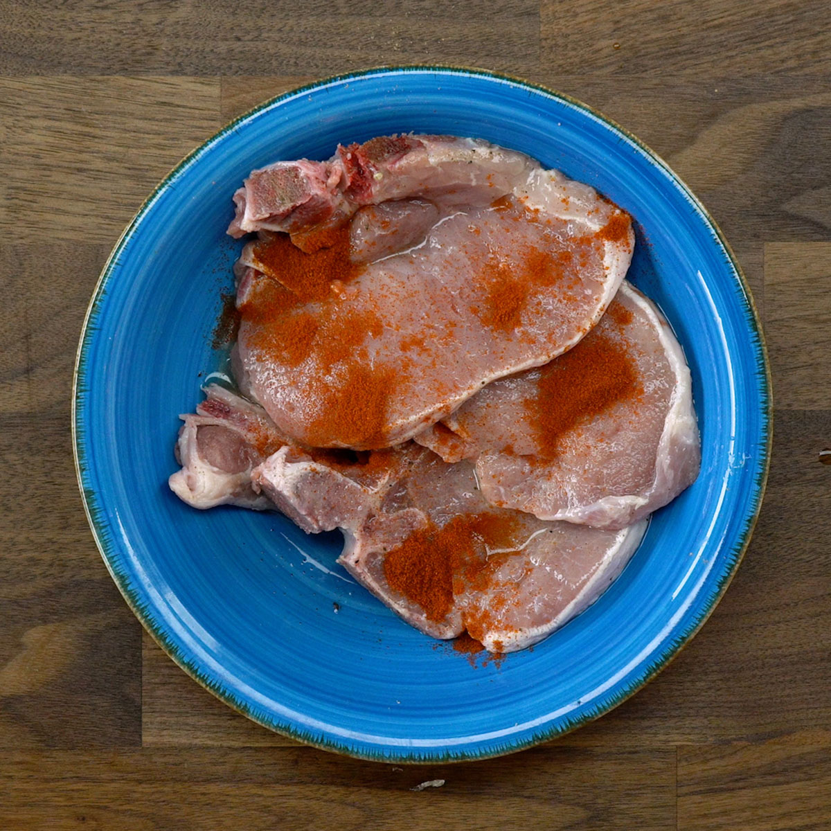 Bistecas de porco sendo temperadas com limão-siciliano, páprica e especiarias.
