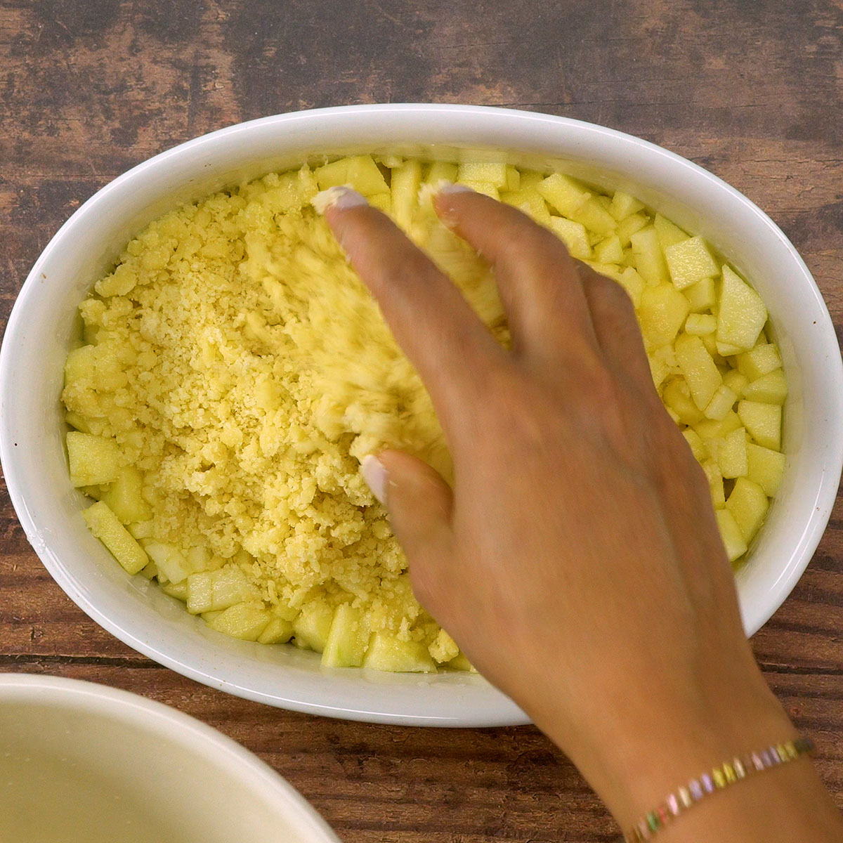 Cobertura de farofa espalhada sobre as maçãs no crumble de maçã.