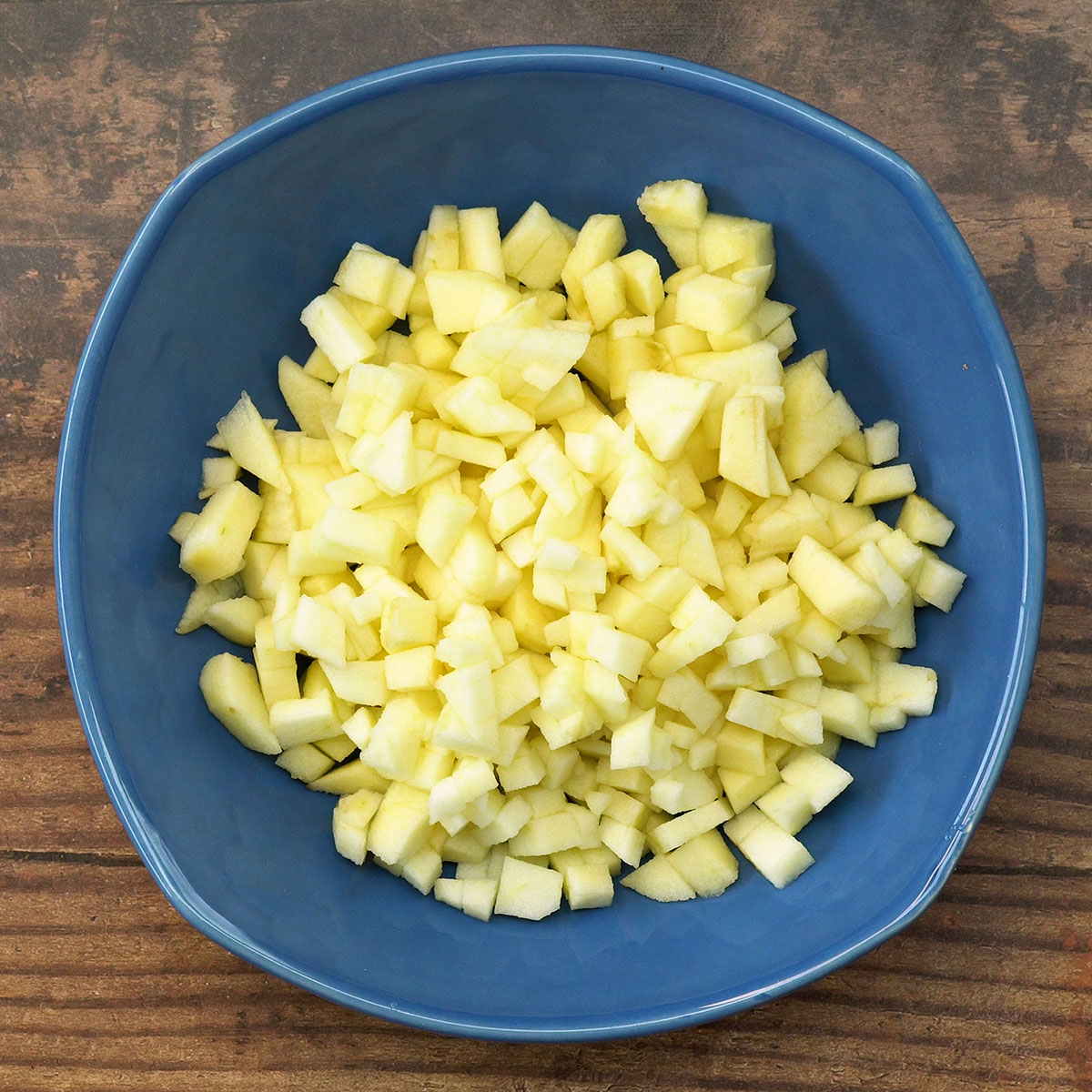 Maçãs descascadas e cortadas em cubos para preparar crumble de maçã.