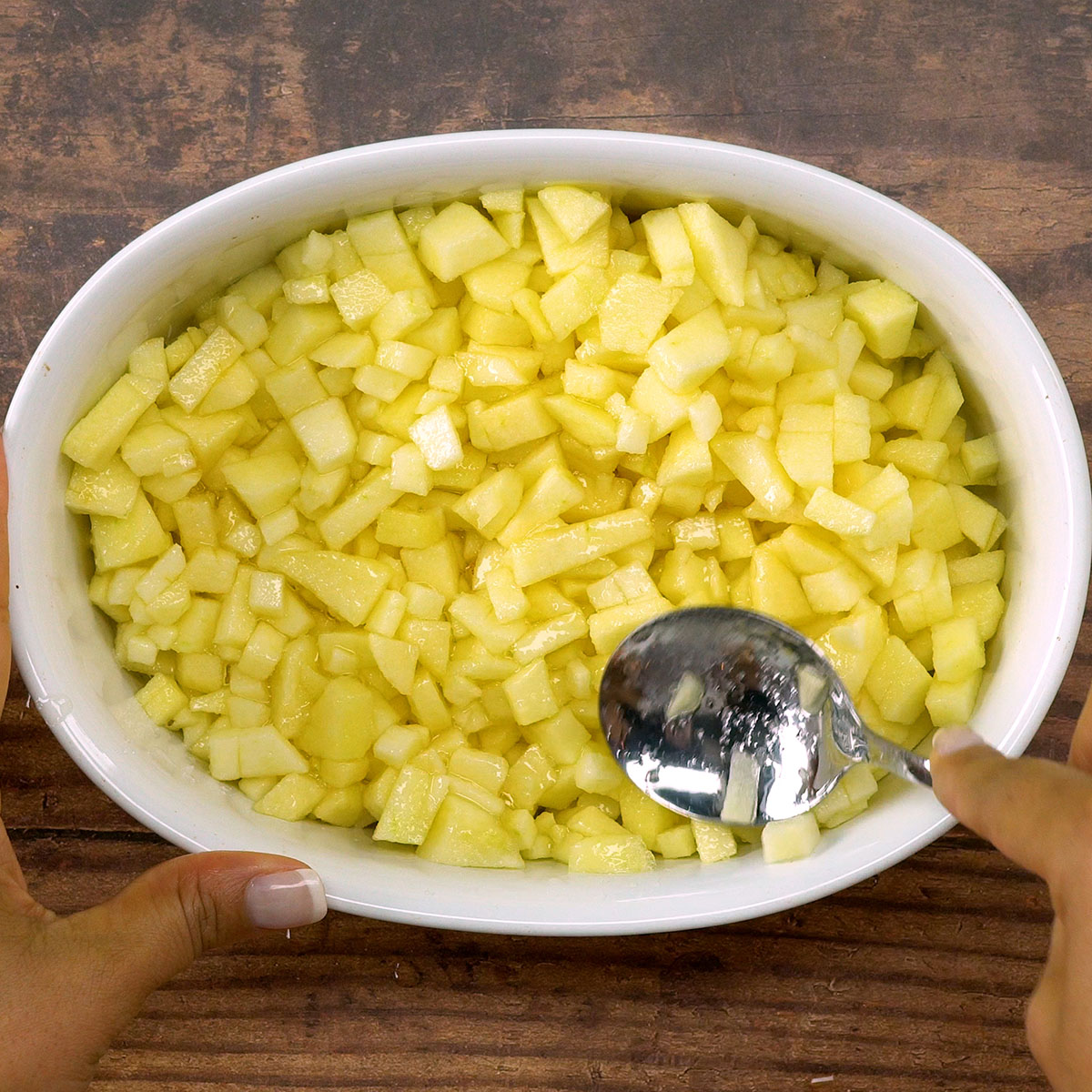 Maçãs temperadas distribuídas no refratário para crumble de maçã.