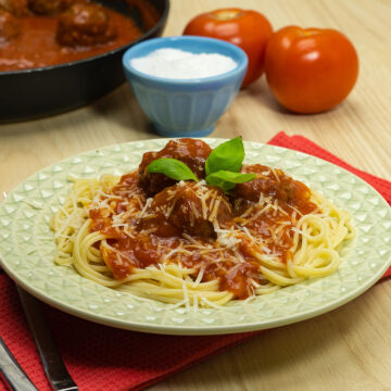 Empratamento almôndegas com sopa de cebola servidas com parmesão e manjericão fresco como decoração.