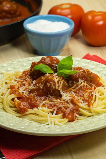 Empratamento almôndegas com sopa de cebola servidas com parmesão e manjericão fresco como decoração.