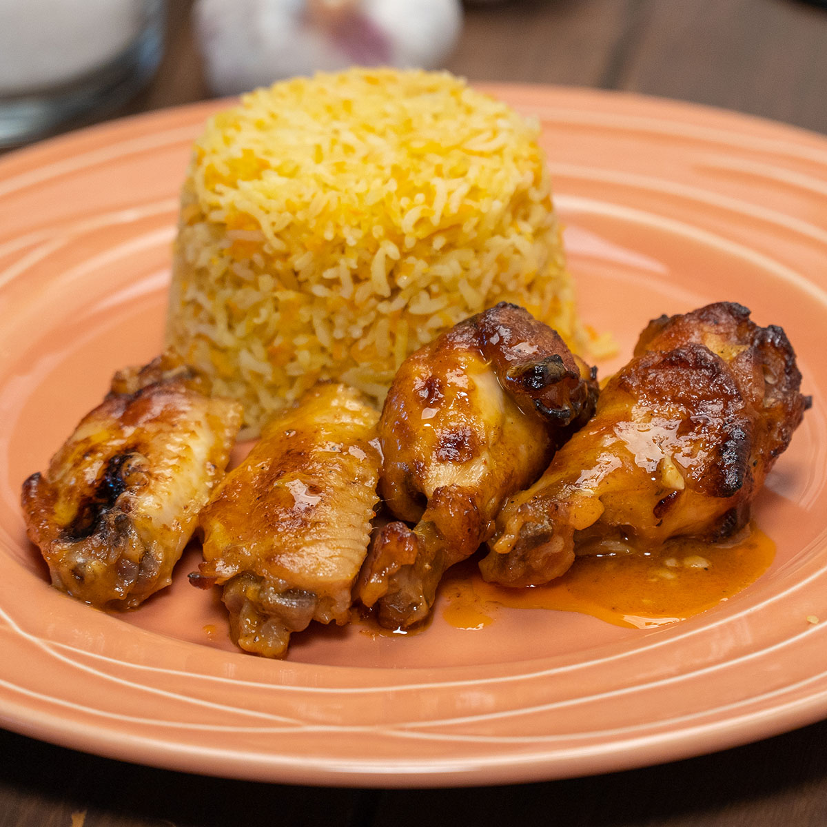 Empratamento asinhas de frango com suco de laranja pronto com arroz de cenoura de acompanhamento.