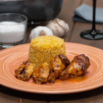 Empratamento asinhas de frango com suco de laranja pronto com arroz de cenoura de acompanhamento.