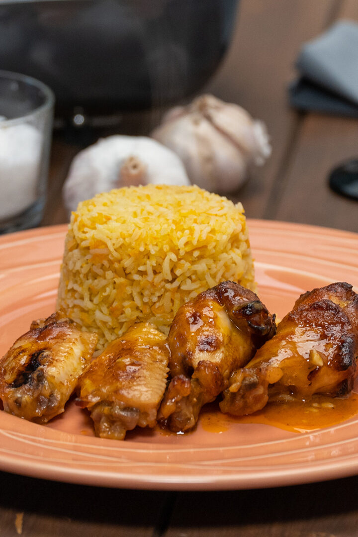 Empratamento asinhas de frango com suco de laranja pronto com arroz de cenoura de acompanhamento.