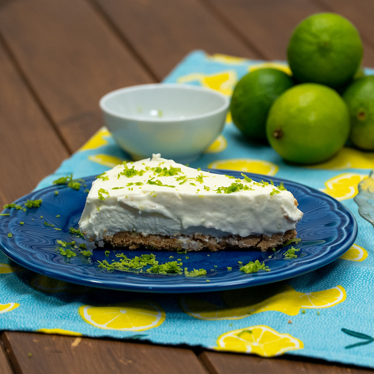 Fatia de cheesecake de limão finalizado com raspas de limão servido no prato.