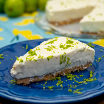 Fatia de cheesecake de limão finalizado com raspas de limão servido no prato.