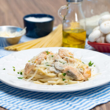 Empratamento linguine com salmão e cogumelo finalizado com queijo parmesão ralado.